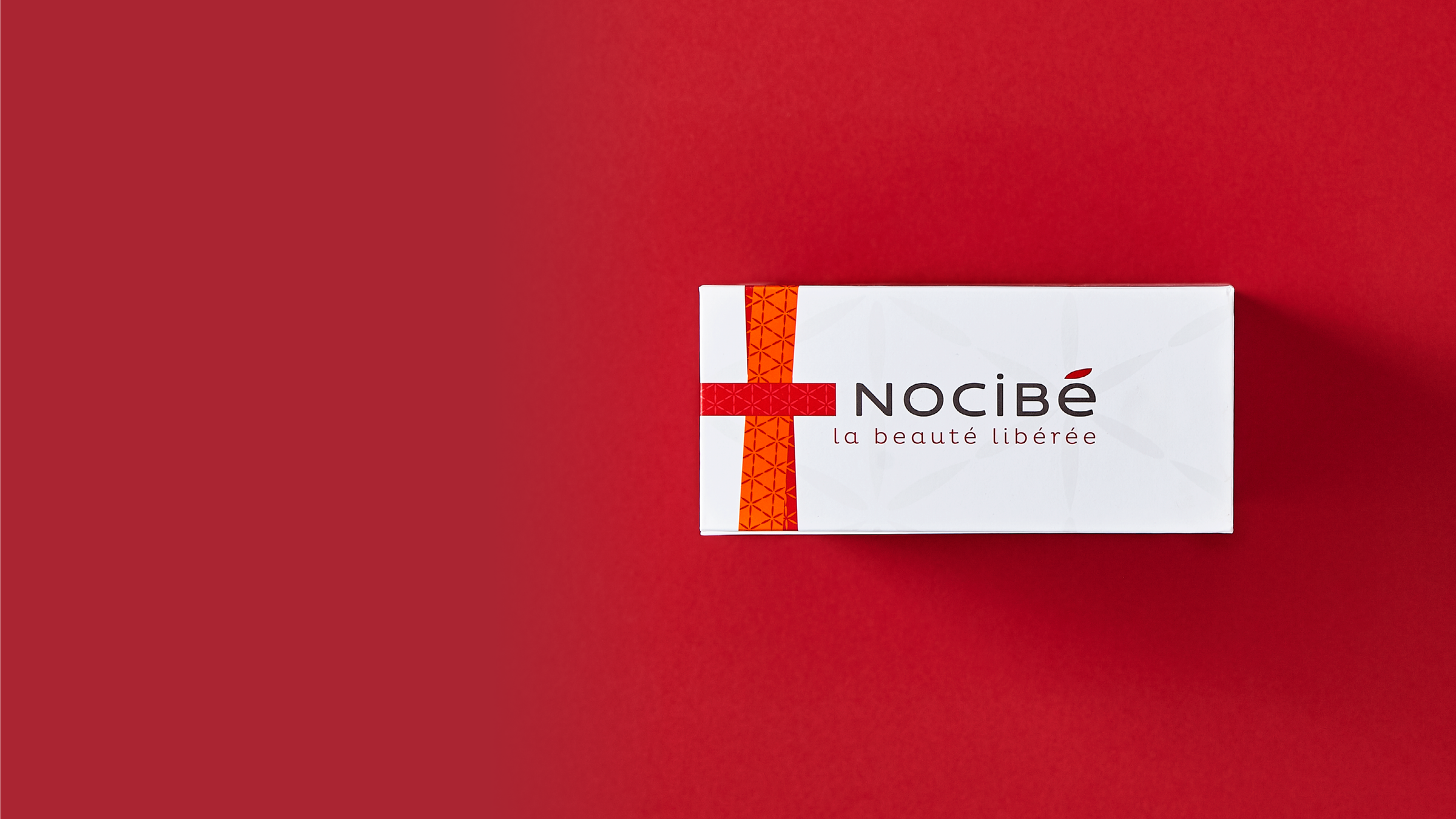 Une boîte en carton blanche avec une fermeture aimantée pour Nocibe sur un fond rouge