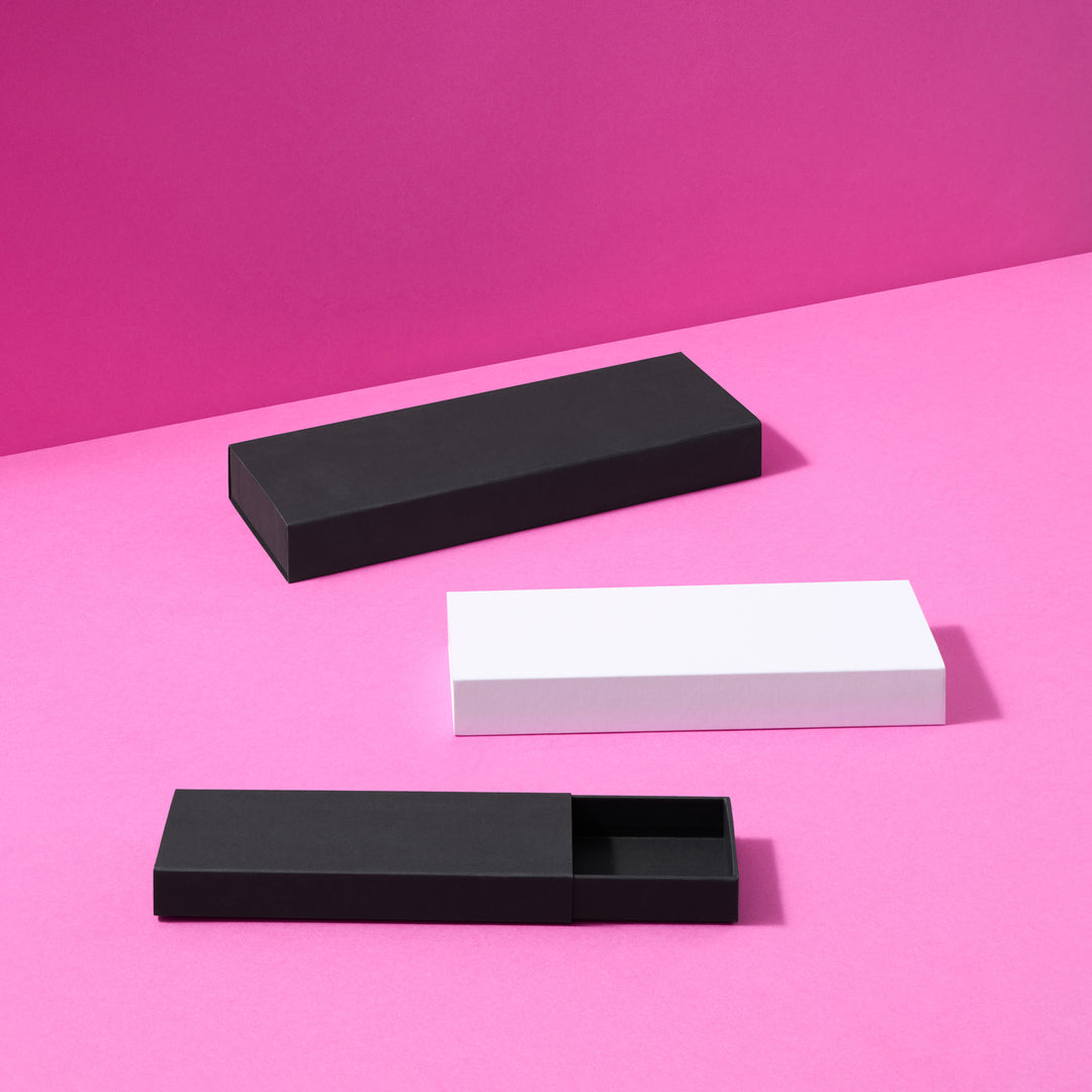 Boîtes-cadeaux de style « boîte d'allumettes » en noir et blanc sur fond rose
