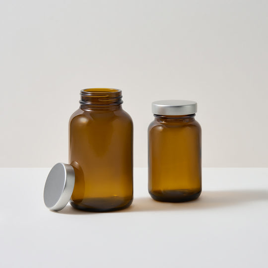 Pots de compléments alimentaires en verre ambré sur fond blanc 

